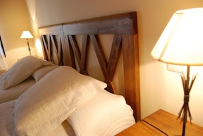 A bed with a wooden headboard, a bedside lamp, and a nightstand.