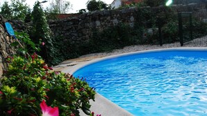 A swimming pool surrounded by greenery and a stone wall. - Casa Rural Las Navillas: vistas a la montaña, Wi-Fi y aire acondicionado (Las Navillas)