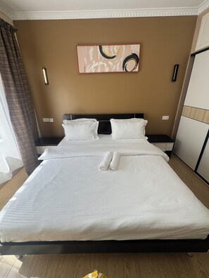Ein Doppelbett mit weißer Bettwäsche, einem Kopfteil und einem Bild darüber.