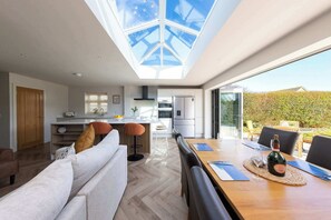 Eine moderne Küche mit Dachfenster, Essbereich mit Tisch für zwei Personen und Blick ins Freie.