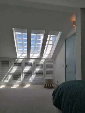 A room with skylights, a bed, a door, and a small stool. - Blue Horizont - Azenhas do Mar (Colares)