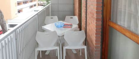 A balcony with a table and chairs, a blue bowl, and a book.