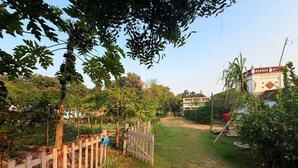 Un jardín con cerca de madera, un sendero y un edificio de fachada roja y blanca.