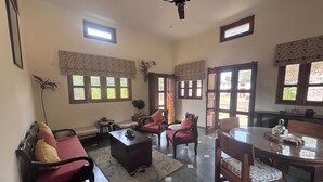 Una habitación con sofá, sillas, una mesa, ventilador de techo y ventanas.