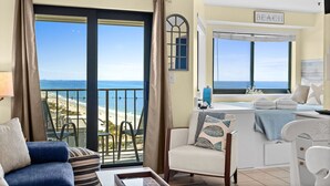 Quarto com vista para a praia, um sofá, uma poltrona, uma mesa e uma cama também com vista.