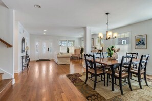 A spacious living area with hardwood flooring, a dining table with chairs, a sofa, and a chandelier. - **New 2026 Rental** Spacious home, walk to beach and town (Lewes)