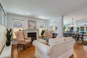 A spacious living room with a fireplace, two armchairs, a sofa, and a dining area with a table and chairs. - **New 2026 Rental** Spacious home, walk to beach and town (Lewes)