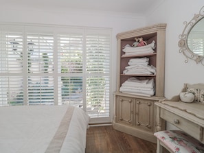 A bedroom with a bed, a wardrobe, a dresser, and a mirror. - 7 The Cedars (Wotton-under-Edge)