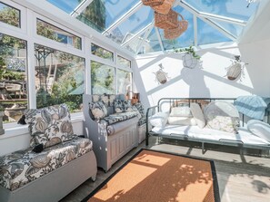 A sunroom with a glass ceiling, a bed, two sofas, and a view of the outdoors. - 7 The Cedars (Wotton-under-Edge)