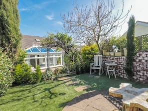 A garden with a conservatory, stone wall, and a wooden bench. - 7 The Cedars (Wotton-under-Edge)