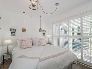 A bedroom with a large bed, two bedside lamps, a hanging light fixture, and a window with blinds. - 7 The Cedars (Wotton-under-Edge)