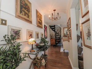 A hallway with framed artwork, a chandelier, a staircase, and wicker baskets. - 7 The Cedars (Wotton-under-Edge)