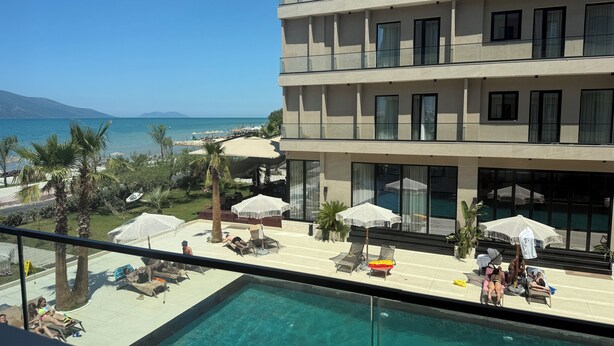 Un hôtel doté d’une piscine, de chaises longues, de parasols et offrant une vue sur la mer.