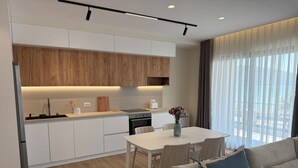 Une cuisine moderne avec des meubles blancs, un plan de travail en bois et un coin repas comprenant une table et des chaises blanches.