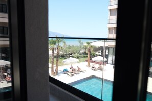 A poolside view with lounge chairs, umbrellas, and palm trees. - Beachfront Apartment (Orikum)