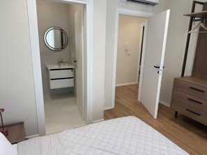 A bedroom with a bed, a dresser, a mirror, and a bathroom with a sink and toilet. - Beachfront Apartment (Orikum)