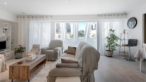 Una sala de estar moderna con un sofá, sillones, una mesa de centro, un televisor y una planta en maceta.