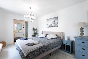 Ein Schlafzimmer mit Bett, Nachttisch, Lampe und einem Wandbild.