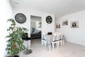 Ein zeitgemäßer Wohnraum mit Essbereich, einem Bett, einer Zimmerpflanze und Wandbildern.