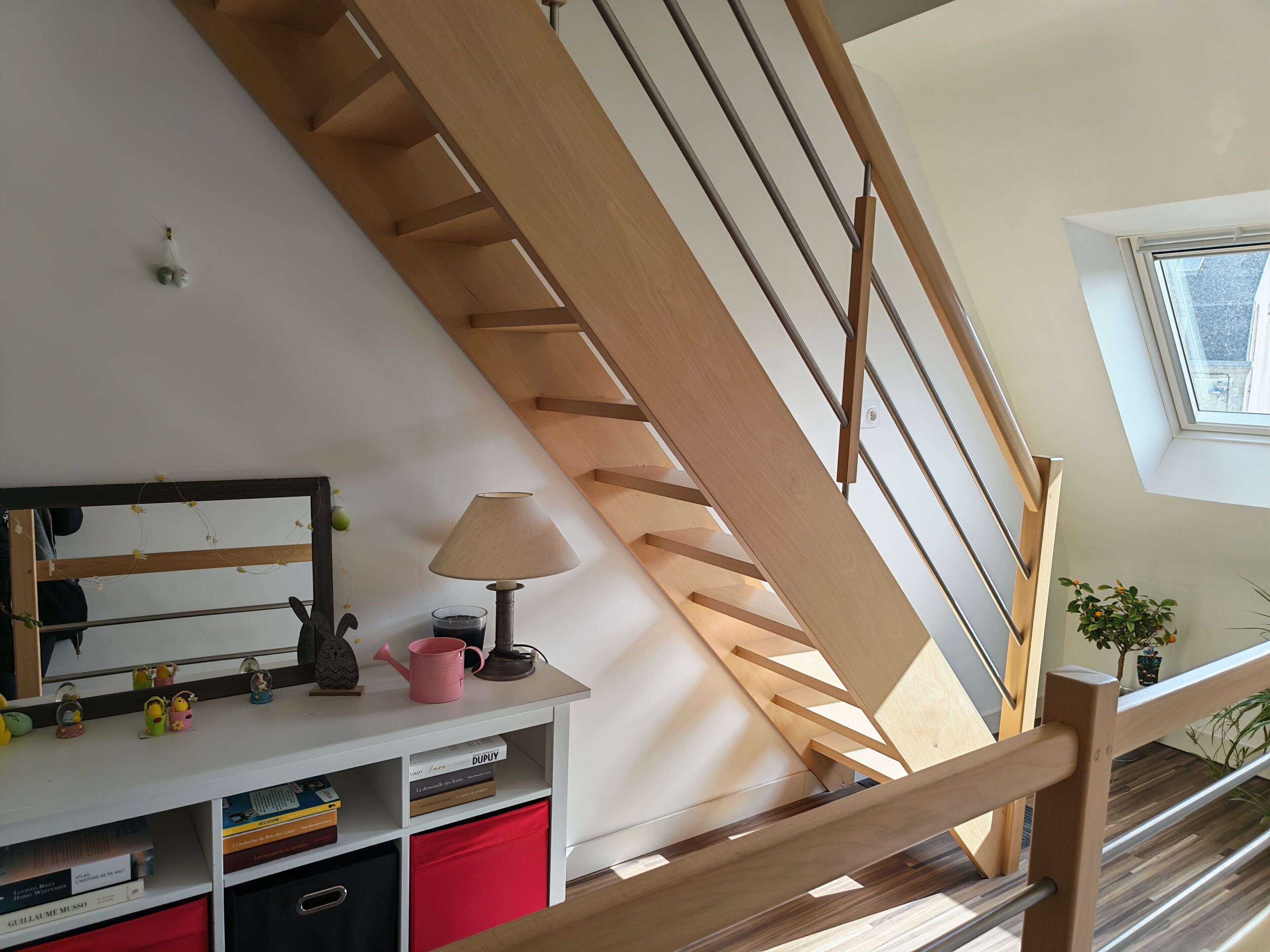 A wooden staircase with a white wall and a window above.