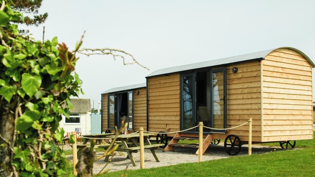 Eine Holzhütte mit gewölbtem Dach, einer Schiebetür und einer kleinen Veranda.