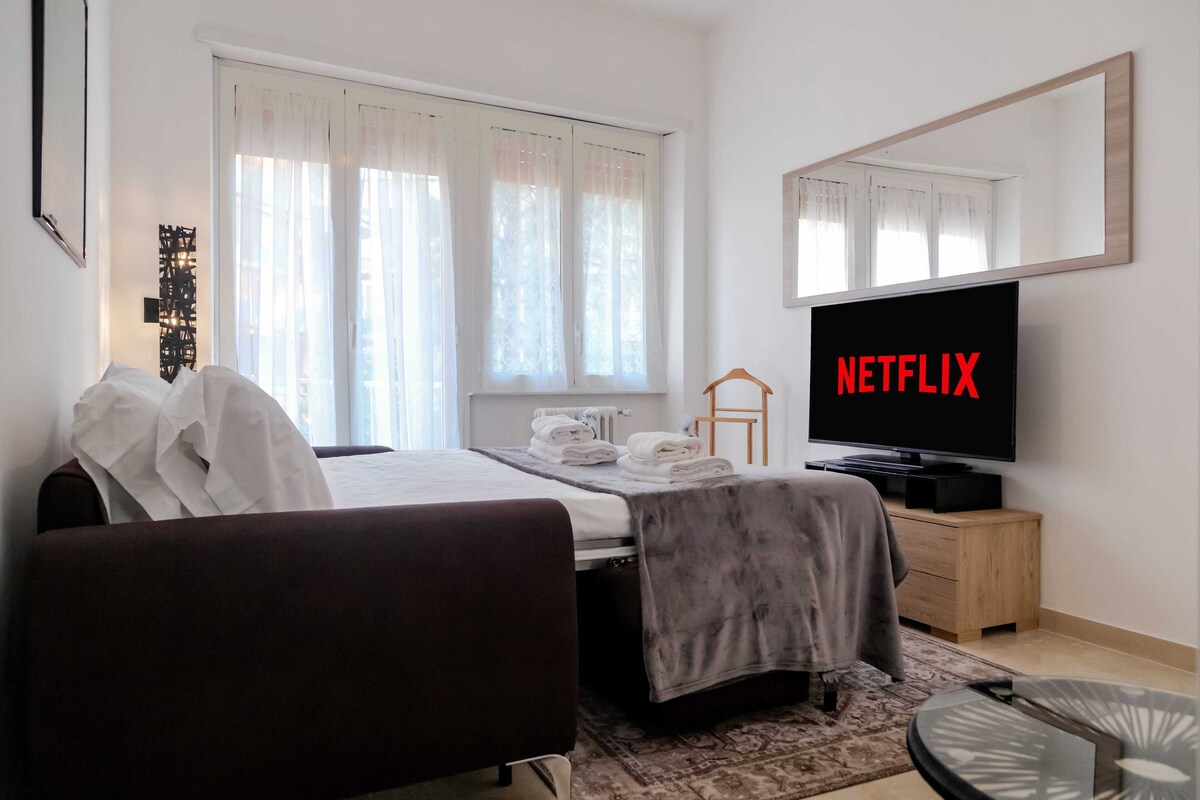 Habitación de hotel con cama, televisor, cómoda y ventana con cortinas.