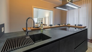 Uma cozinha moderna com uma ilha grande, eletrodomésticos de aço inoxidável e um exaustor embutido.