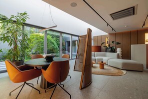 A modern interior with a dining area, a sofa, and a large window overlooking greenery. - Stylish Apartment | 2 Bedrooms, Parking and Gym (Katowice)