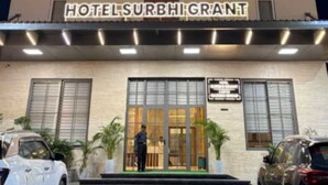 Ett hotell med en skylt där det står ”HOTELSURBHIGRANT” och en person som står vid ingången.