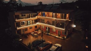 A multi-story building with balconies, outdoor seating, and a car parked in front. - Hotel Mahabaleswer Mount View (Mahabaleshwar)