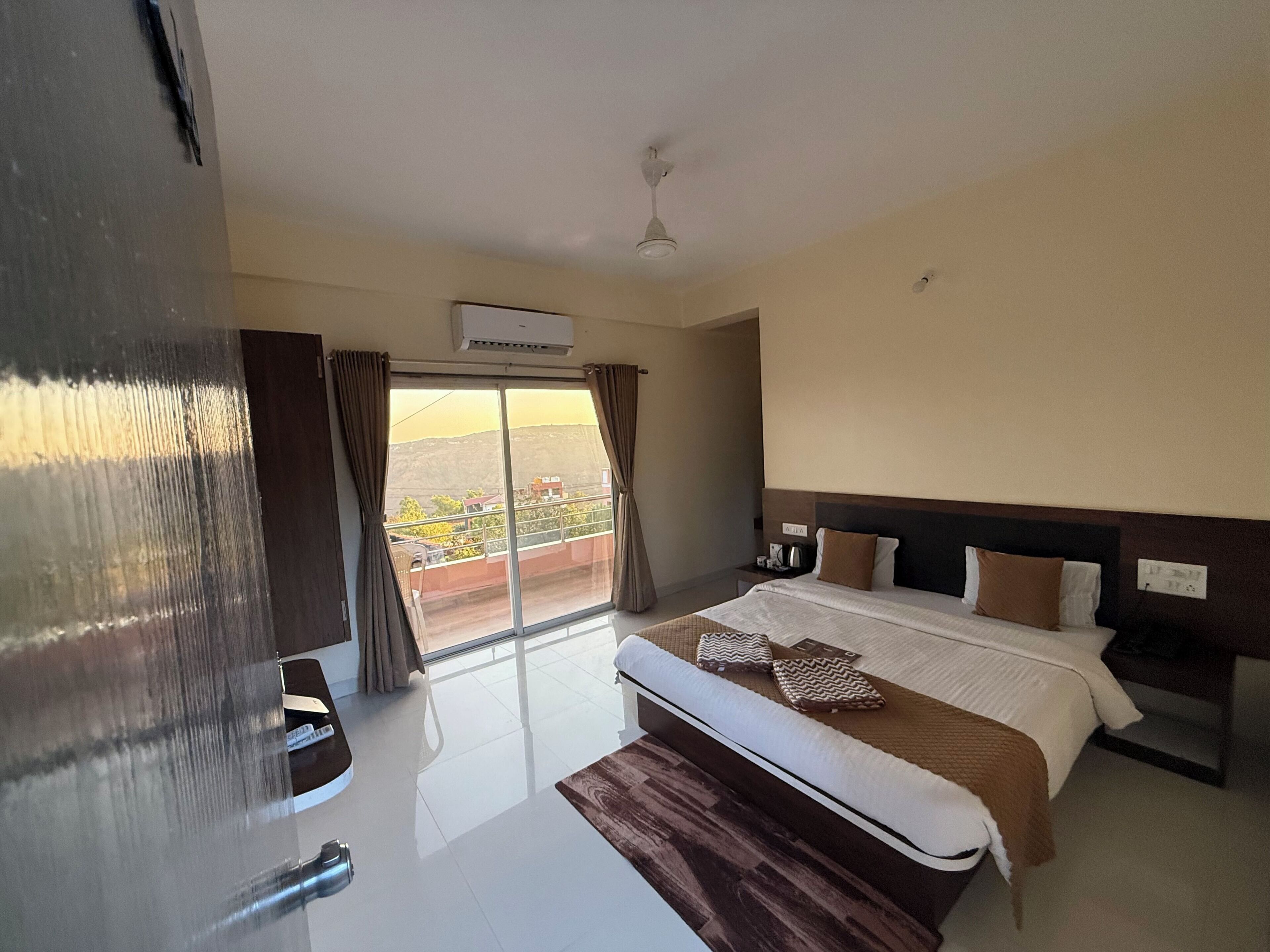 Habitación de hotel con cama, mesita de noche, ventana con cortinas y ventilador de techo.