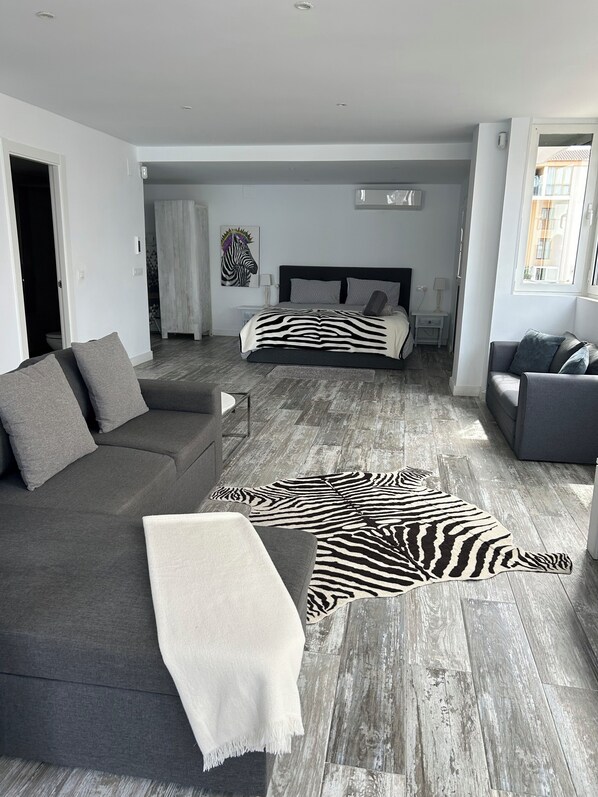 A modern living room with a sofa, a zebra-patterned rug, a bed with a zebra-themed headboard, and a grey couch. - Modern Studio apartment in the center of Moraira (VC)