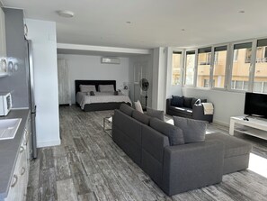 A modern bedroom with a bed, bedside table, and a TV. - Modern Studio apartment in the center of Moraira (VC)
