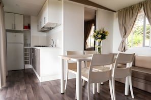 A modern kitchen with white cabinets, a built-in oven, and a dining area with a table and chairs. - Sea View - 40 Parallelo Mobile Home (Camerota)