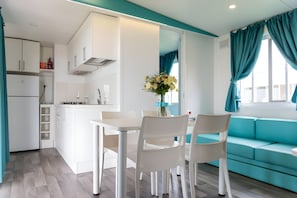 Une cuisine moderne avec des meubles blancs, une table à manger avec des chaises et un canapé de couleur turquoise.