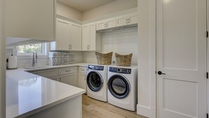 Una cocina moderna con lavadora y secadora integradas, armarios blancos y una ventana.