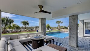 Un área exterior con piscina, sofá y ventilador de techo.