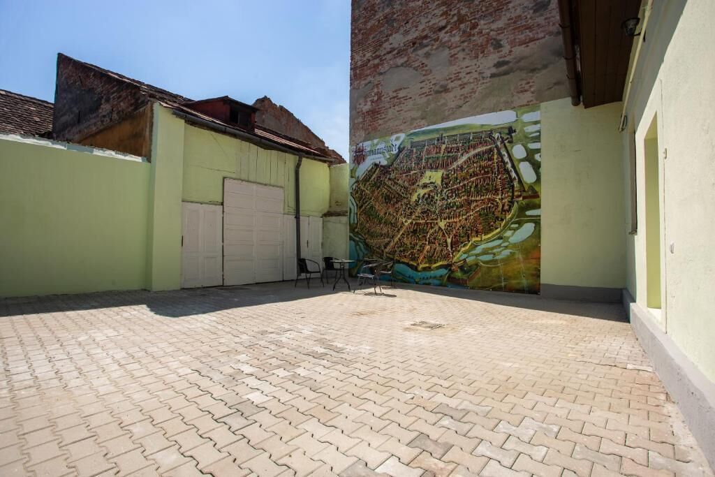 Ein Innenhof mit Pflasterboden, einem Wandgemälde und einem Gebäude mit einer Garagentür.