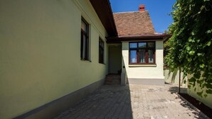 A narrow alleyway leading to a building with a tiled roof and a small staircase.