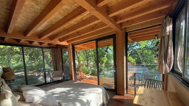 Una baita di legno con un letto, un tavolo e una sedia.