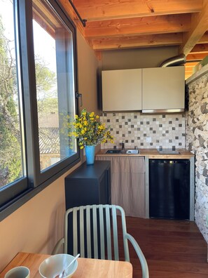 A compact kitchen with a window, a sink, a dishwasher, and a dining area with a chair and table. - Le Nid in Provence (Le Puy-Sainte-Réparade)