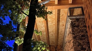 Una scala in legno con pareti in pietra, una porta in legno e un albero in primo piano.