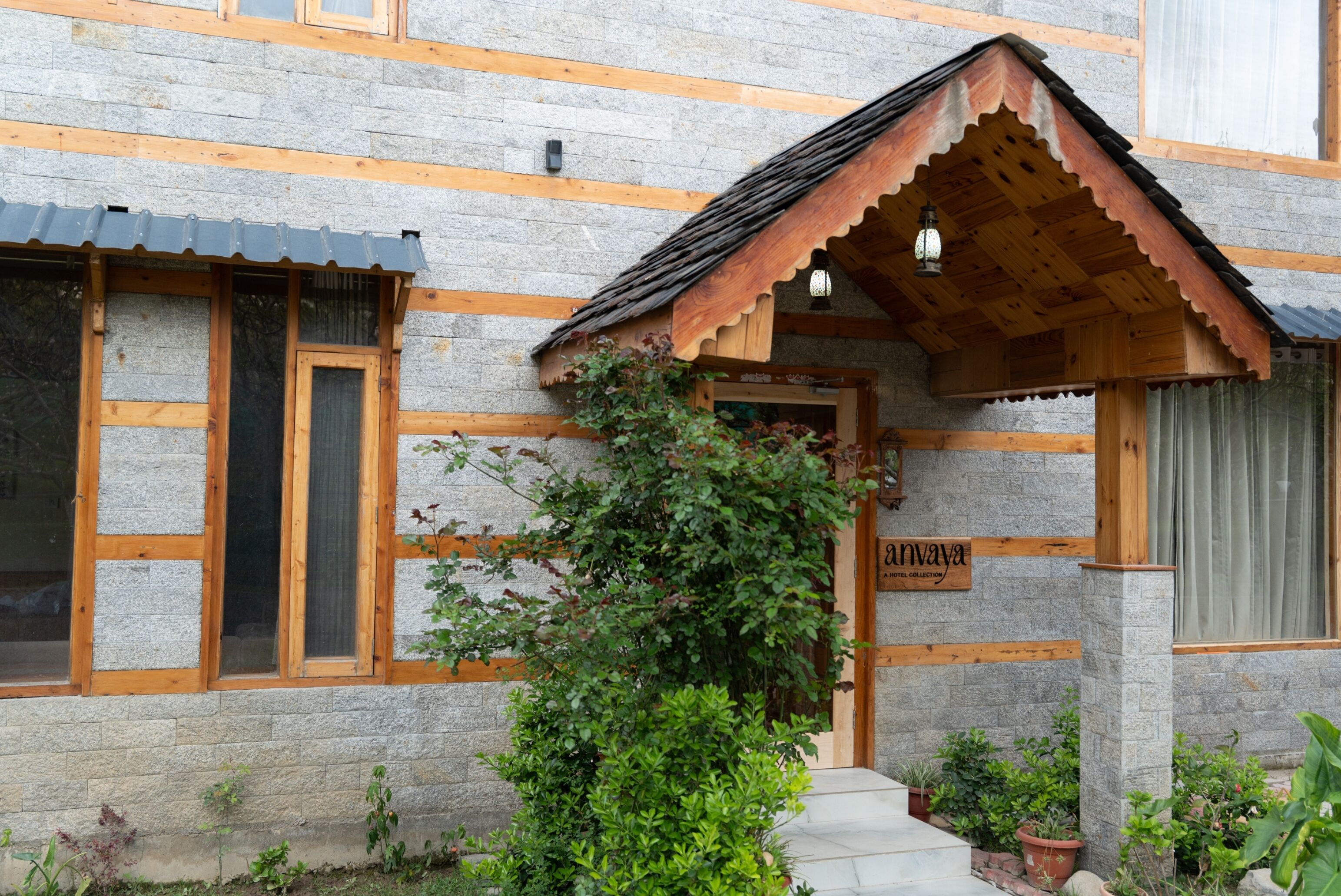 A stone building with wooden beams, a wooden porch, and a sign reading 'Anvaya.'