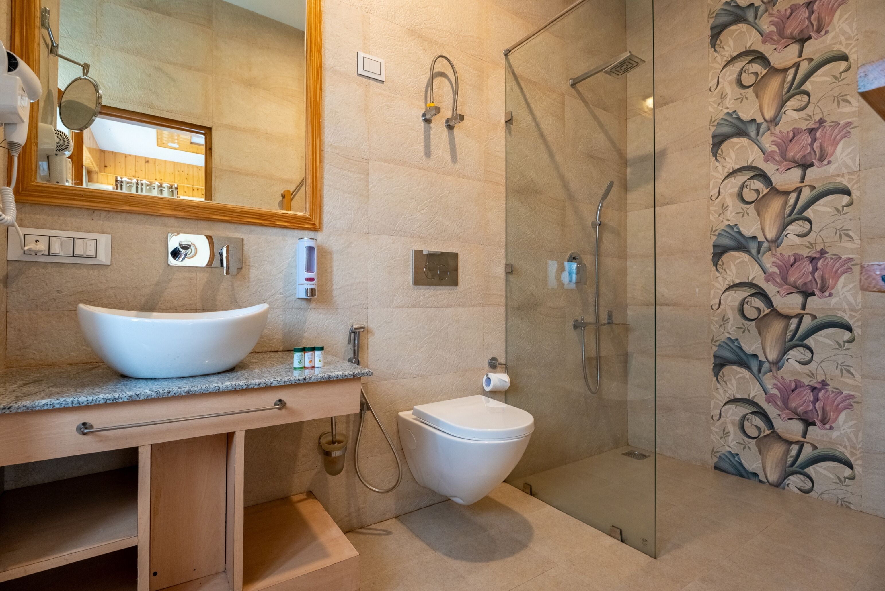 A modern bathroom with a large mirror, a white sink, a toilet, and a glass-enclosed shower area.