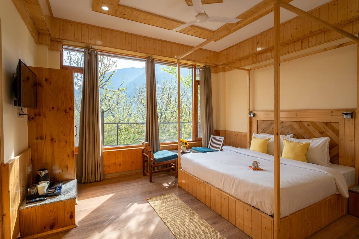 A wooden-paneled bedroom with a bed, a desk, and a chair.
