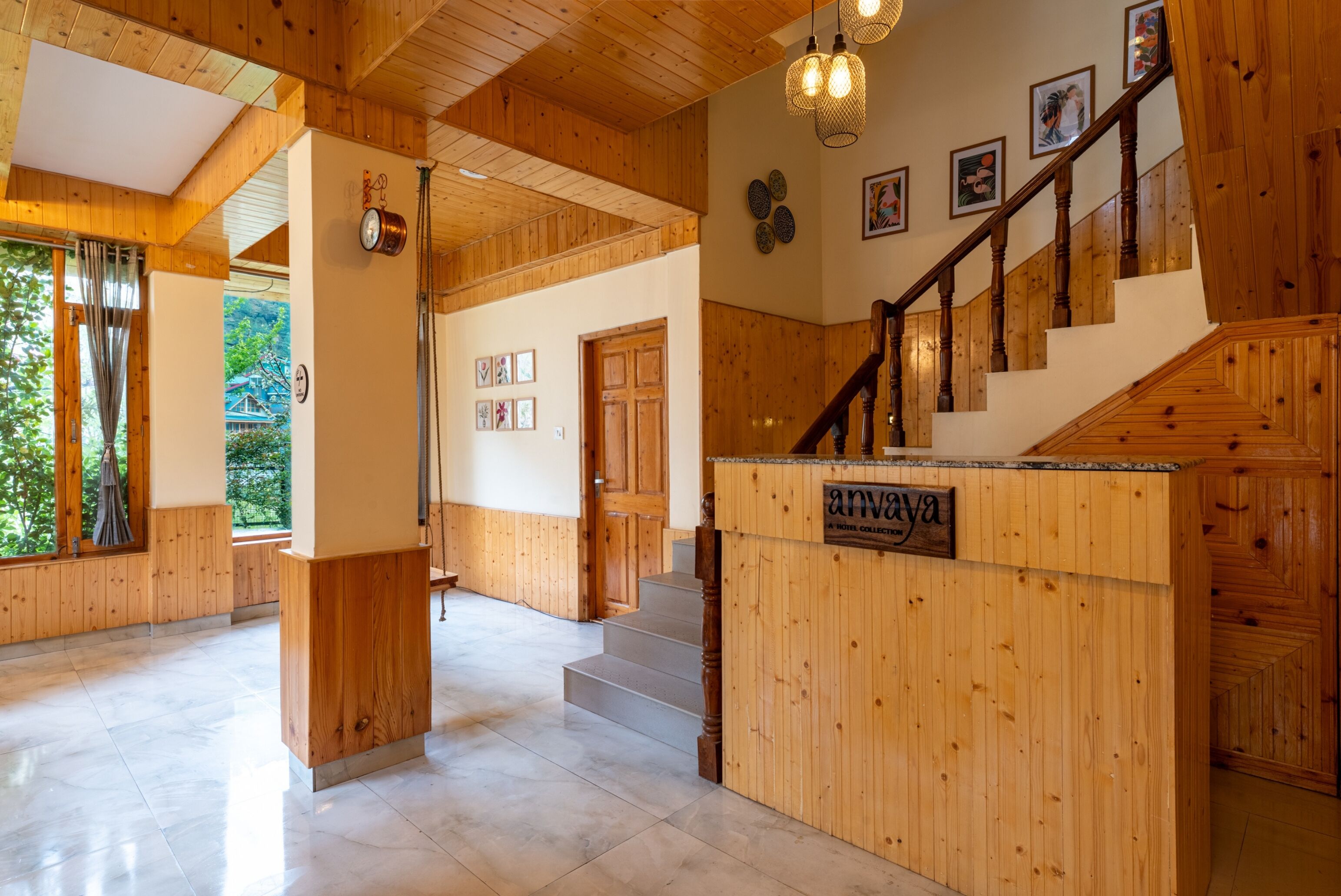 Ein Holzinnenraum mit einer Rezeption, einer Treppe und gerahmten Bildern an den Wänden.