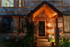 A rustic building with a wooden facade, a porch with a wooden roof, and a sign reading 'anvaya.' - Anvaya Manali - Luxury Mountain Retreat (Manali)