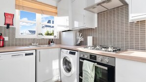 Een moderne keuken met een vaatwasser, wasmachine, oven en kookplaat.