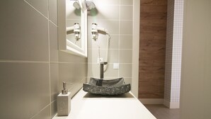 Un baño moderno con un lavamanos blanco, un espejo y un secador de pelo fijado en la pared.