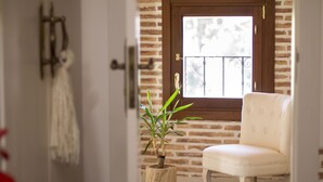 Un interior con puerta de madera, una silla blanca y una planta en maceta.